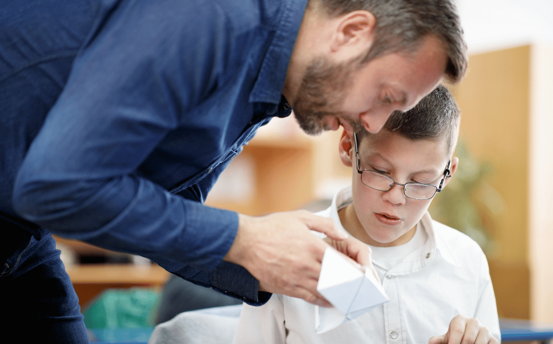 male teacher works with a boy in school uniform