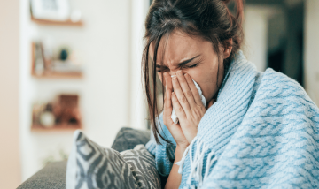 woman in blue blanket sneezing