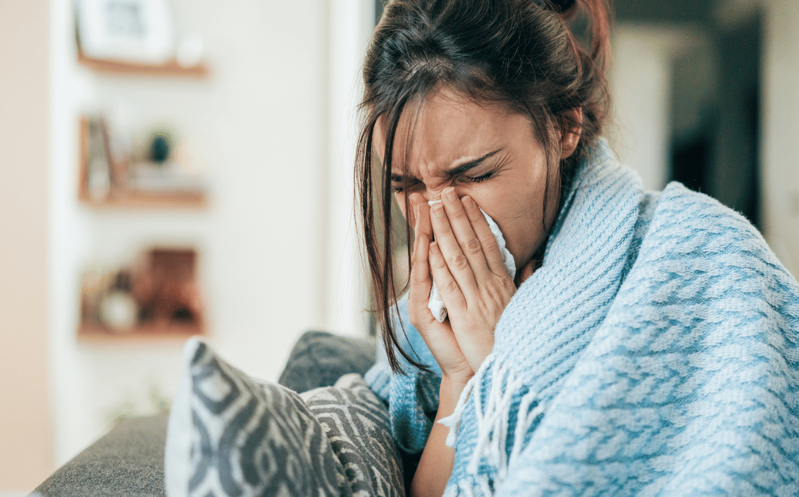 woman in blue blanket sneezing