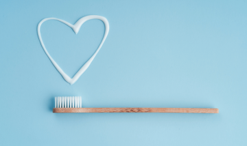 toothbrush with a heart drawn in toothpaste on blue background