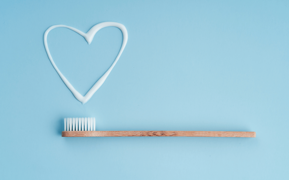 toothbrush with a heart drawn in toothpaste on blue background